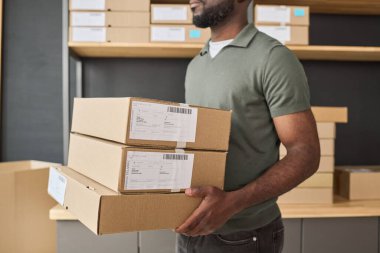 Afrika 'lı adamın elinde karton kutular taşıyarak depoya teslim edişinin yakın çekimi.