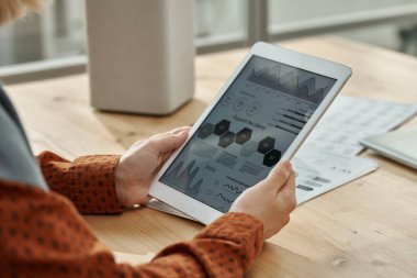 Ofiste otururken tablet bilgisayarındaki grafikleri inceleyen iş kadınının yakın çekimi
