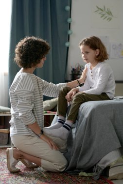 Genç anne, onlar yatak odasında otururken zor çocuğuyla konuşuyor.