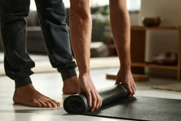 Close-up of barefoot man preparing mat for yoga exercises in the room at home