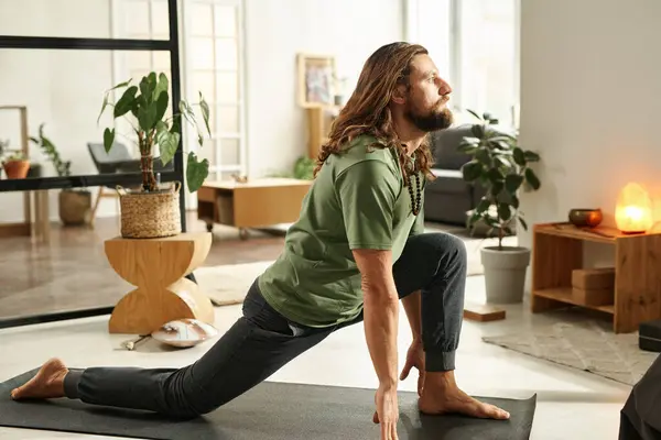 Young barefoot man practicing yoga exercises on exercise mat in the morning at home