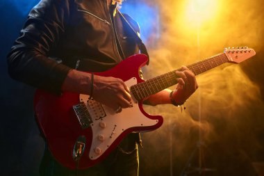 Sahnede, dumanlı neon ışıklarla elektro gitar çalan tanınmayan olgun rock müzisyenlerine yakın çekim yapın.