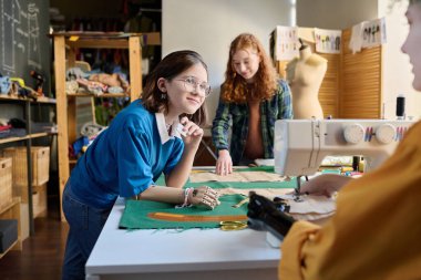 Çeşitli kız grupları birlikte kıyafet dikerken aynı zamanda okuldaki fotokopi odalarında dikiş dikmenin keyfini çıkarıyorlar.
