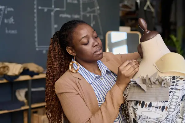 Portrait of African American woman as tailor fitting designer clothes on mannequin in atelier copy space