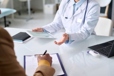 Tıbbi klinikteki fotokopi odasında muayene sırasında hasta kartlarını imzalayan tanınmayan Orta Doğulu adamı kapatın.