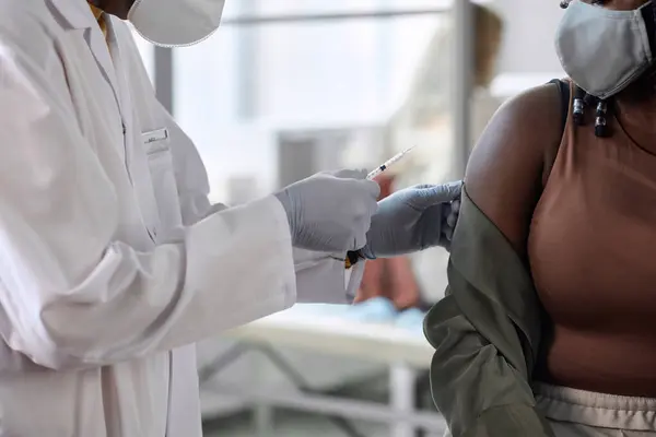 无法辨认的非洲裔美国妇女在诊所注射疫苗的特写镜头 图库图片