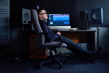 Kulaklıklı yorgun teknisyen iş yerindeki koltukta dinleniyor.