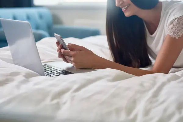 一个快乐的年轻女人躺在床上边看书边笑 免版税图库图片