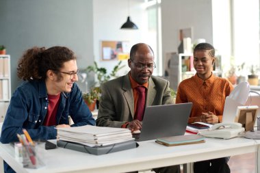 Üst düzey Afro-Amerikan bir adamın portresi. Katılımcı ofis düzeninde dizüstü bilgisayar kullanıyor.