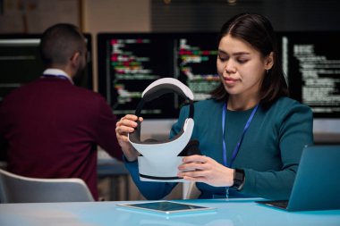 VR kulaklık takan genç bir kadının portresi ofiste yeni teknolojiler geliştirirken arka planda kod ekranları, kopyalama alanı