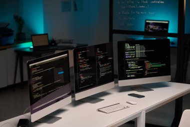 IT Geliştirme Ofisi 'nin arkaplan resmi ve masadaki üç bilgisayar monitörü mavi ışıkta, boşluğu kopyala