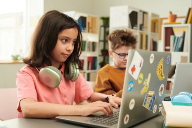 Modern okul kütüphanesinde bilgisayar kullanan genç kız portresi bilişim ve kopya alanı programlarken