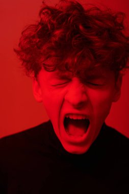 Bağıran yüz hatları olan, yoğun kırmızı ışıkta yıkanmış, güçlü duygu ve enerji taşıyan biri.