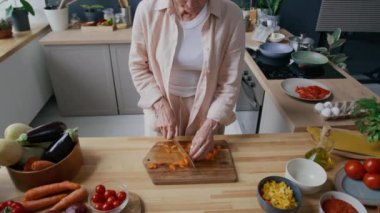 Tanımlanamayan bir kadının havucu doğradığı ve sağlıklı yemek hazırlıkları sırasında kaseye bıçakla doldurduğu sahneler. Sıcak mutfakta, ahşap tezgahın üzerinde taze malzemelerle.