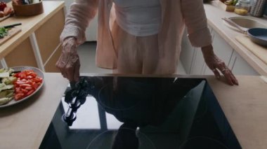 Modern mutfak tezgahında elinde tavayla domates ve kabak da dahil olmak üzere taze doğranmış sebze tabağıyla tanınmayan bir kadın şefin kırpılmış görüntüsü.