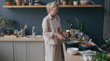 Kafkas kadın şefin modern mutfakta yemek pişirirken tavada kıyma pişirme işleminin tadını çıkardığı orta boy bir fotoğraf.