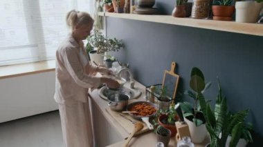 Orta yaşlı, beyaz bir kadının pişirdikten sonra kevgire makarna sürdüğü ev yapımı bolonez soslu spagetti hazırladığı bir fotoğraf.