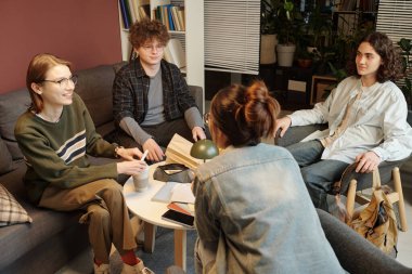 Bir grup üniversiteli arkadaşın okul salonunda ödev yaparken sohbet edip abur cubur yemesi.