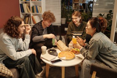 Okul salonunda ev ödevi yaparken abur cubur yiyen arkadaş grubuna yüksek açılı bir bakış açısı.