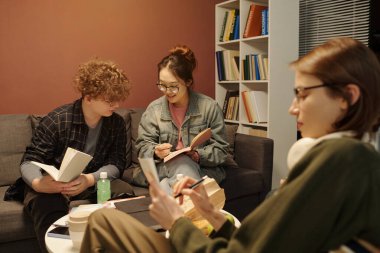 Asyalı genç kız oğlanla notlarını paylaşıyor. Öğrenci salonunda birlikte okuyorlar.