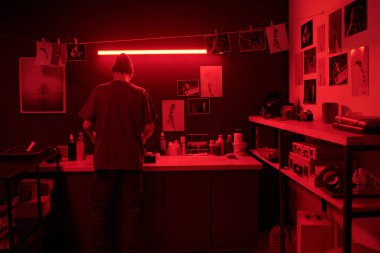 Karanlık odada kırmızı neon ışıklı fotokopi alanı tarafından aydınlatılan fotoğrafları geliştirirken, yaratıcı süreçte genç fotoğrafçıların arka planı
