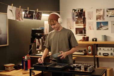 Geleneksel fotoğrafçılık ve kulaklık takarak kimyasalları karıştıran genç bir çocuğun portresi.