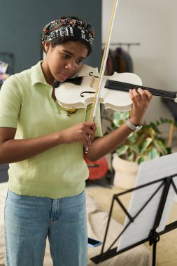Kemana odaklanan genç bir kız. Kapalı alanda rahat bir ortamda durması için notalar çalıyor. Yeşil gömlek, saç bandı ve konsantrasyon müziğe adanmışlığı gösteriyor.