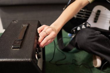 Bas gitar çalarken insanların el ayarlama ayarlarını kapat, düğmeleri çeviren parmakları göster, müzik ekipmanlarına odaklan ve enstrümanla etkileşime gir