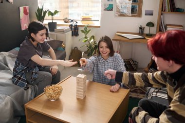 Masada atıştırmalıklarla otururken masa başında oyun sırası beklerken taş kağıt makas oynayan üç gençten oluşan bir grup.