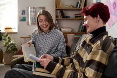 Yurt odasındaki çalışma sırasında elinde kitap olan ve arkadaşlarıyla sohbet eden gülümseyen genç kızın portresi.