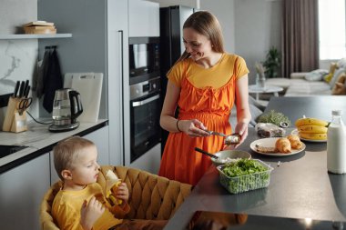 Sabahları birlikte sağlıklı bir kahvaltı ederken annesinin küçük oğluna gülümsemesini yüksek açıdan izlemek.