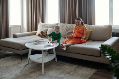 Anne ve çocuğun oturma odasındaki büyük kanepede oturup öğleden sonra eğlendiği samimi bir sahne.