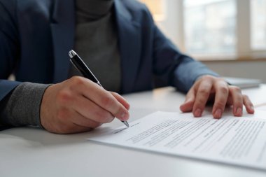 Tanımlanamayan bir işadamının elinde kalem yeri olan bir erkeğin ofiste sözleşme imzalaması.