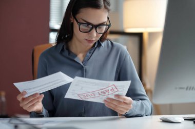 Finansal belgeleri sıralayan genç bir iş kadınının portresi ve elinde eski pullarla vergi beyannamesi tutuyor.
