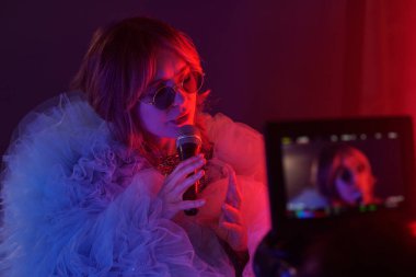 Stüdyoda klip çekimlerinde genç şarkıcının mikrofon tutarken ve duygusal sahneler çekerken orta boy portresi.