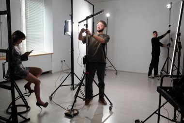 Film ekibinin, stüdyoda video çekimi için ışık ve profesyonel ekipman kurarken geniş açılı görüntüsü.