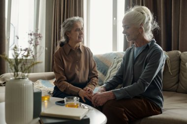 İki yaşlı kadın sıcak bir oturma odasında birlikte oturup anlamlı bir konuşma yapıyor ve sıcak bir anı paylaşıyorlar. Vazo, kitap ve cam kaplı masa ön planda sade atmosferi arttırıyor.