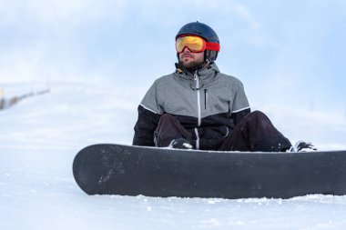 Kayak merkezinin yamaçlarında snowboard yapan genç bir adam.
