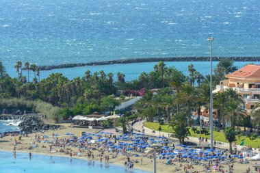 Los Cristianos, Tenerife, Kanarya, İspanya 2014 16 Kasım: mavi şemsiye ve şezlong üzerinde kentsel kıyı şeridi vardır. Atlantik Okyanusu üzerinde ince kum ile ünlü Kent plajları vardır