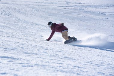 Genç kadın snowboardcu dağlarda snowboard yapıyor.