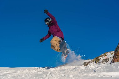 Genç kadın snowboardcu dağlarda snowboard yapıyor.