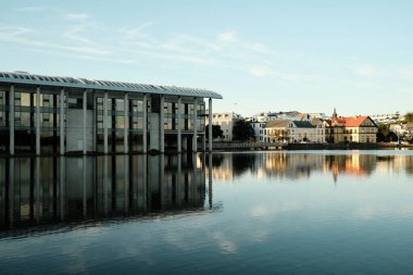 Reykjavik 'teki belediye binası ve güneşli bir günde berrak nehrin yanında bulunan eski evler.