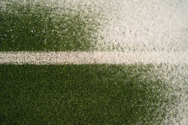 Soğuk kış gününde beyaz çizgili çimenli futbol sahasının üst manzarası taze karla kaplıydı.