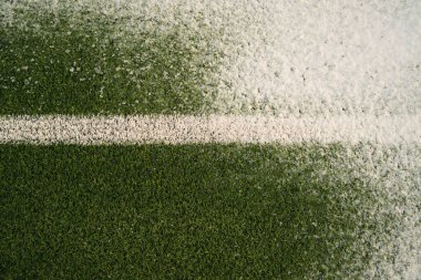 Top view of grassy football pitch with white line covered with fresh snow on cold winter day clipart