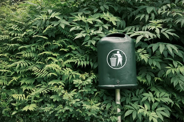 公园小巷里 在茂密的灌木绿叶中安装有图标的金属垃圾箱 — 图库照片