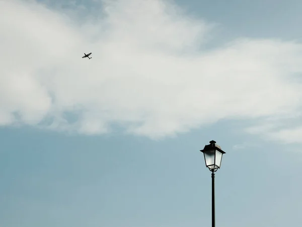 空を飛ぶ飛行機のシルエットと白い雲の下にミニマリストの黒のシンプルなランタンの下から — ストック写真