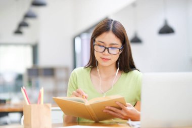 Genç Asyalı kız öğrenci evde bilgisayar kullanarak ve internetten öğrenerek okuyor. Evde dizüstü bilgisayarla iş dünyası bağımsız video konferansı.