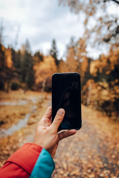 男人用你的智能手机拍了一张秋天风景的照片 — 图库照片