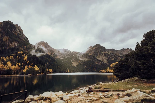 Montanha Lado Lago Algumas Árvores Durante Dia Nublado — Fotografia de Stock