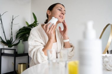 Kadın, evinde yüzünde mikro akım cihazı kullanıyor.